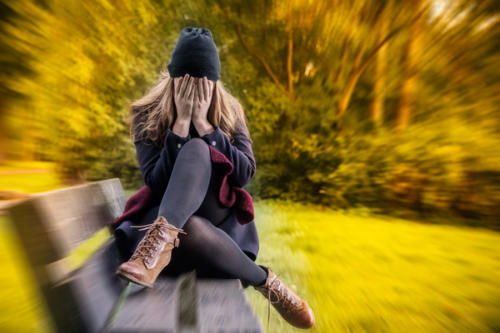 Young lady on a bench looking very anxious and worried
